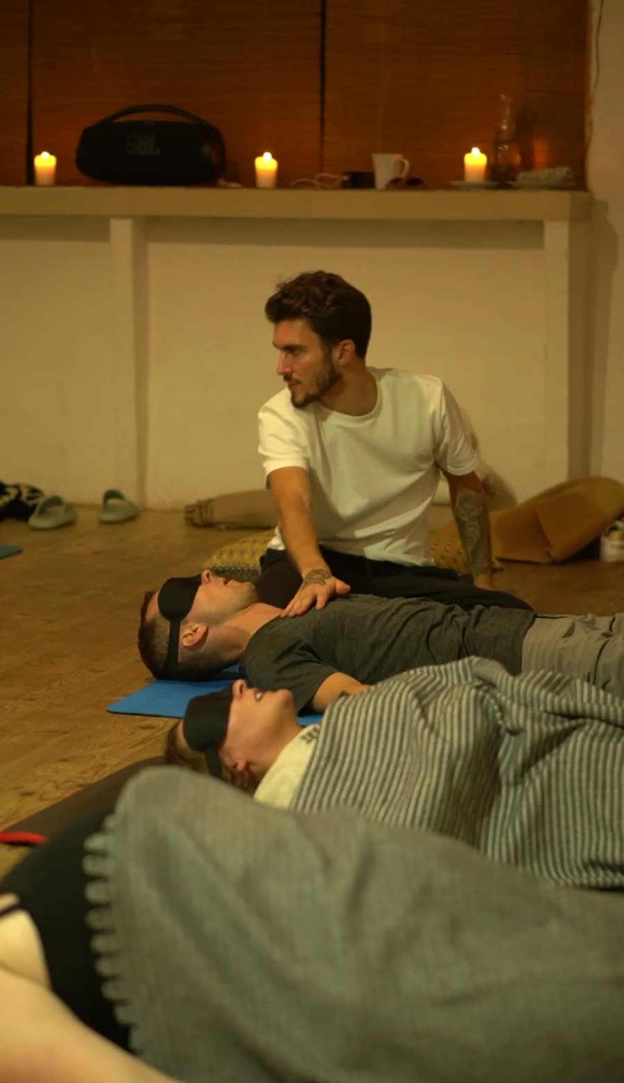 Valentin legt im Kerzenlicht einer liegenden Teilnehmerin die Hand auf die Brust